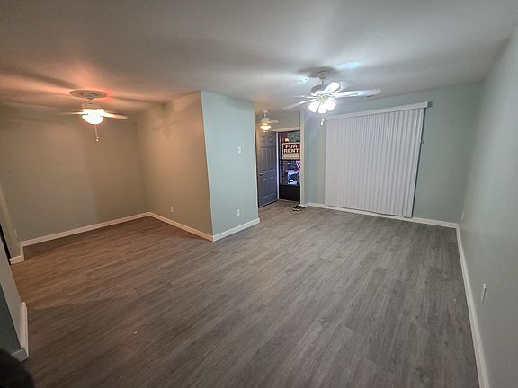 View of living room and dining room facing out to entrance with vertical blinds, and fan lights