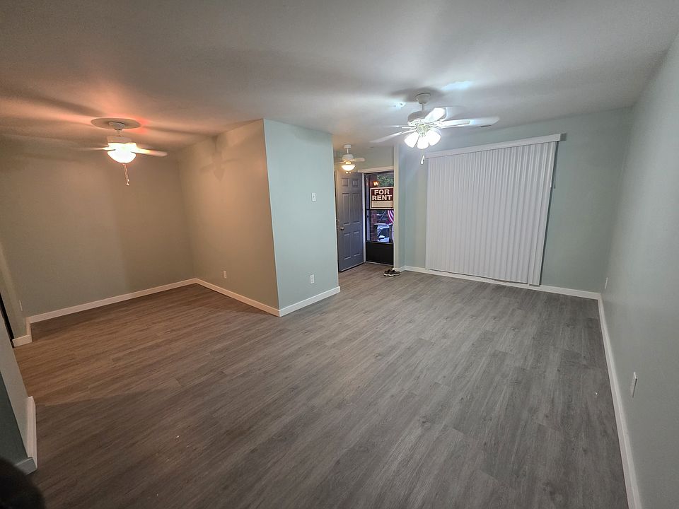 View of living room and dining room facing out to entrance with vertical blinds, and fan lights