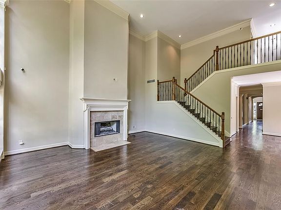 Alternate view of Family Room emphasizing the wrought iron staircase, gas fireplace and beautiful hardwood floors throughout.