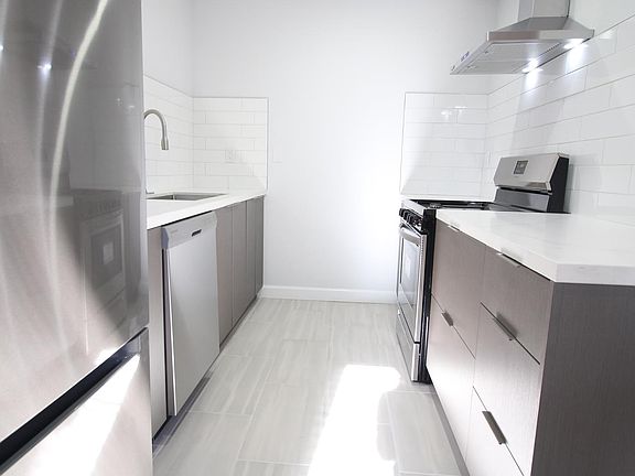 Looking down the kitchen. Stainless steel fridge and dish washer on the left. Stove and hood on the right. Plenty of storage.