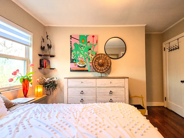 Master bedroom with original artwork and smart tv (mounted on wall across from king sized bed)