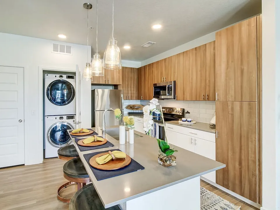 Kitchens feature oak upper and white lower cabinetry, grey quartz countertops, white subway tile backsplash, kitchen island or breakfast bar, and luxury vinyl plank flooring