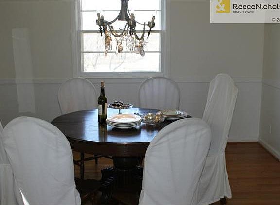 Kitschy formal dining room with chandelier and hardwood floors.