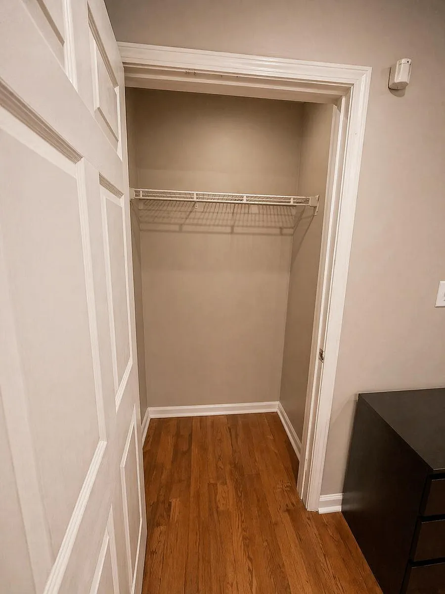 Bedroom closet with a hanging shelf and open floor space for luggage, bins, or a compact dresser. - Custer Ave SE