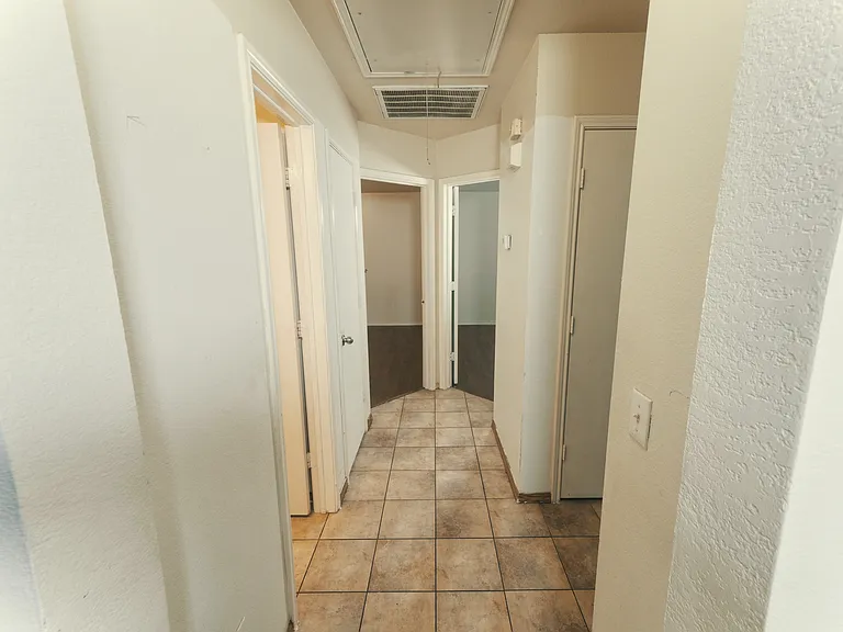 A functional central hallway with durable tile flooring provides easy access to three guest bedrooms, a full-sized bathroom, and the attached 2 car garage