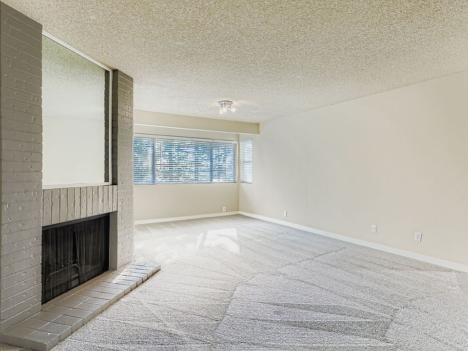 Living room with wood burning fireplace and new carpet.