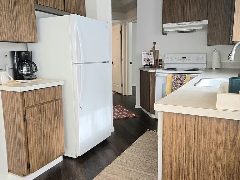 Additional view of galley kitchen. Ample cabinetry. Towards laundry, bathroom, and N. bedroom. (rugs and staging items not included).
