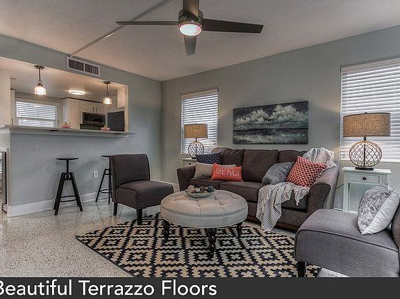 Image of a spacious living area with terrazzo flooring and a view of the kitchen area.