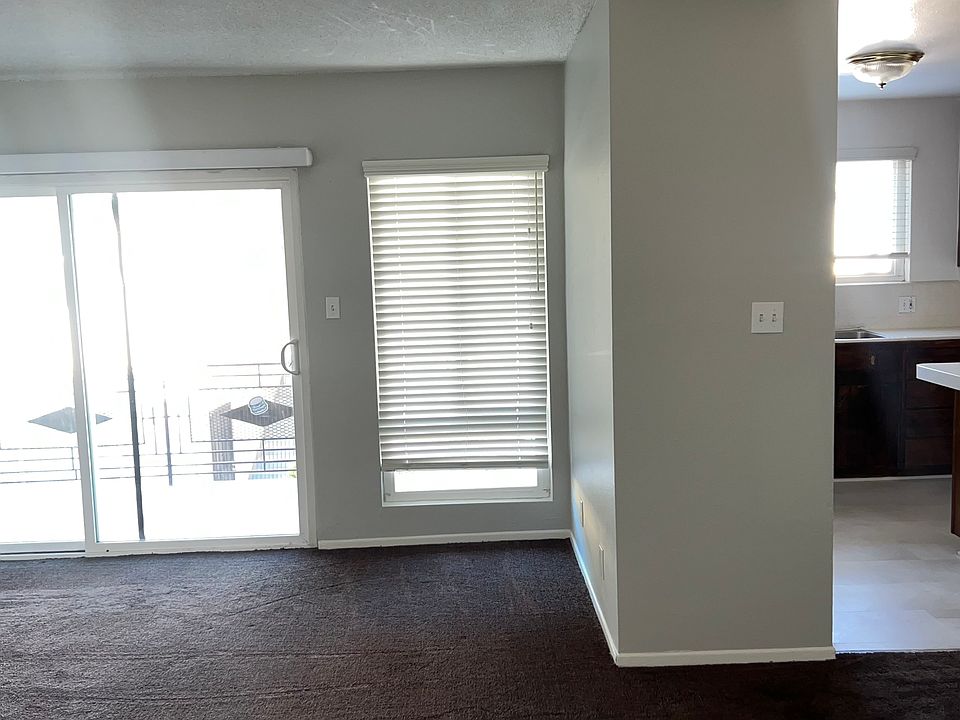 Living room with balcony on left and kitchen to right
