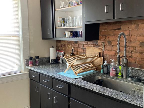 kitchen with Granite tops stainless under-mount sink and bull out faucet and cool exposed brick walls
