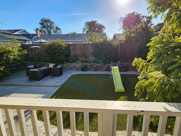 Backyard with low maintenance artificial turf and many trees