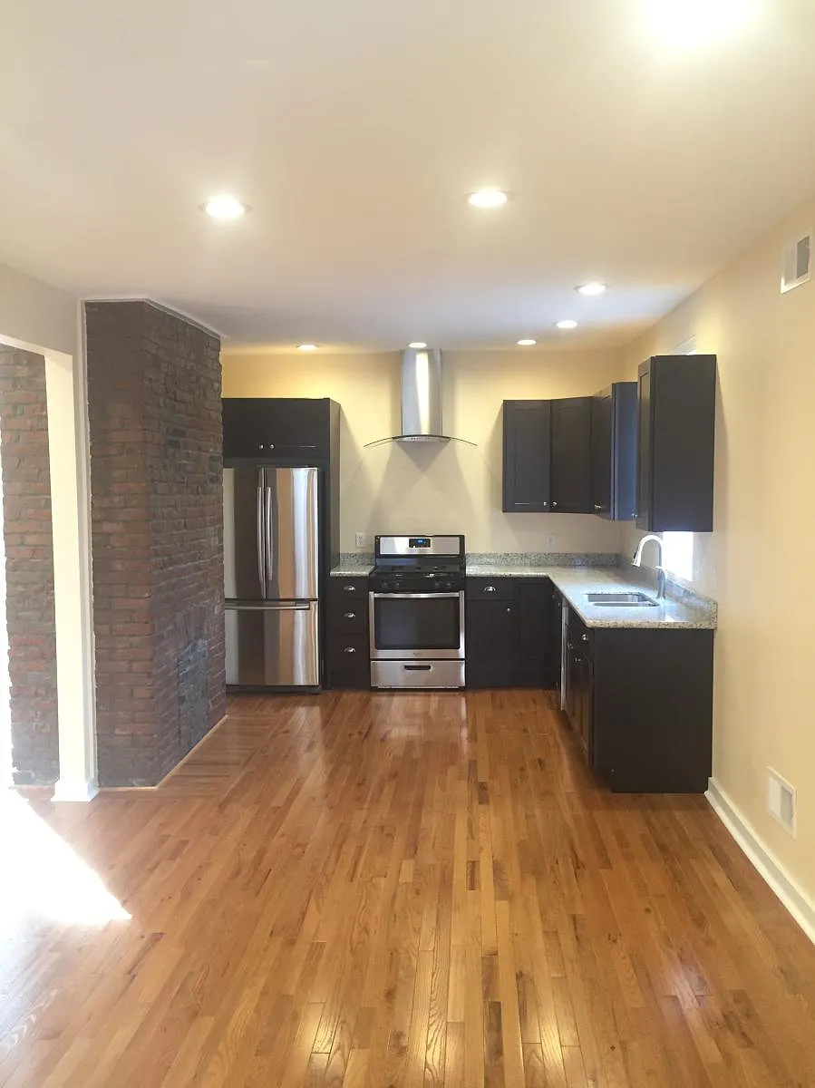 Sleek designer kitchen with rich dark cabinetry, granite countertops, and stylish finishes that bring warmth and sophistication to the heart of the home. - 310 Darsie St