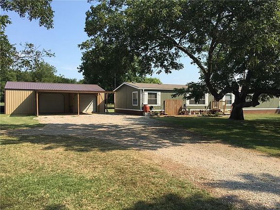 Front with shop/garage/carport and mature pecan tree.