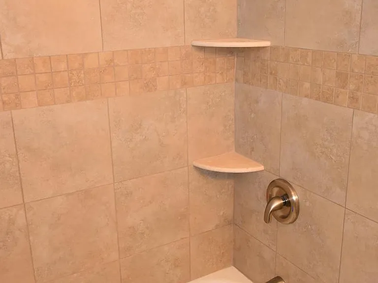 Bath: Porcelain tile & tub, Moen bath & shower fixtures, toiletry shelves