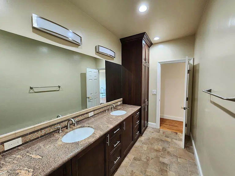 View from toilet/shower room to guest bathroom #1 with upgraded tile work, custom cabinetry and dual sink vanity.