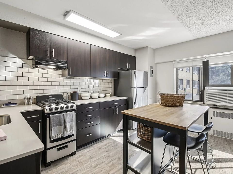 This kitchen features black cabinets and white appliances, as well as a wooden table