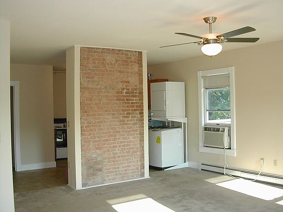 Open Living room Kitchen separated by exposed brick partition wall.