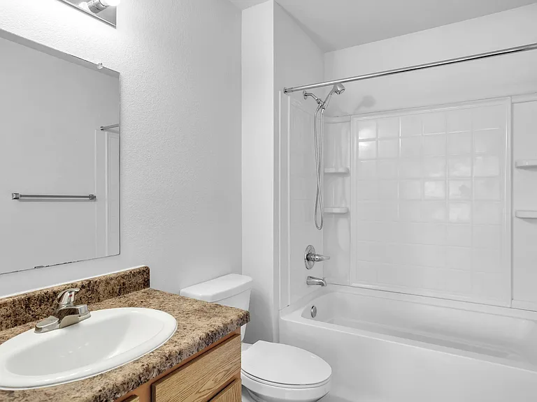 Modern bathroom featuring sleek countertop, elegant sink, and a pristine bathtub with integrated shower. Modern bathroom featuring sleek countertop, elegant sink, and a pristine bathtub with integrated shower.