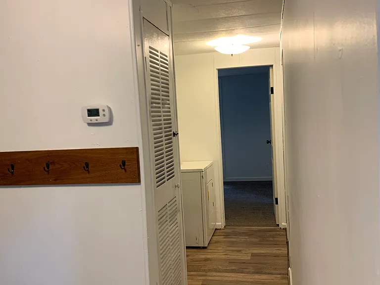 Hallway showing storage closet and door to second bedroom. Washer and dryer are on the left. Rear door is on the right.