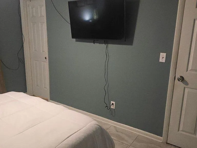 Private bedroom with tile flooring, a mounted TV, and convenient access to nearby closet and interior doors.