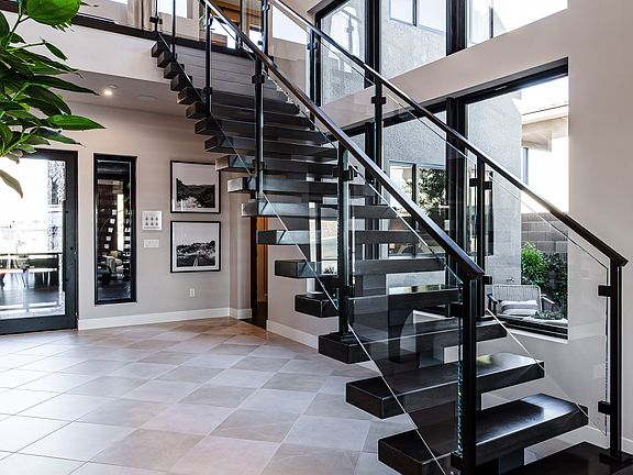 A modern and spacious entryway with a grand staircase featuring sleek black metal railings and steps
