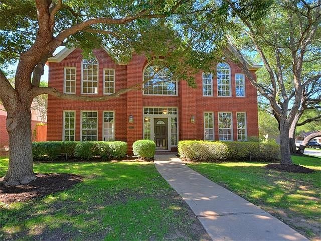 Beautiful red brick home surrounded by mature oak trees.