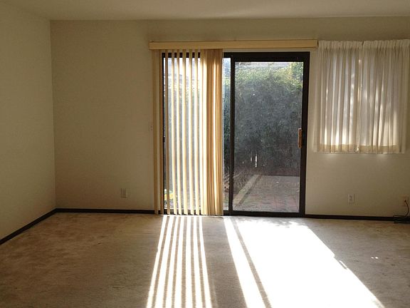 A spacious living room on the first floor leading to a paved and fully fenced yard