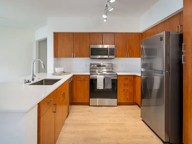 Renovated Package I kitchen with cherry cabinetry, white quartz countertops, stainless steel appliances, upgraded lightning, and hard surface flooring
