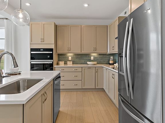 View of the kitchen showcasing a stainless steel sink and dishwasher attached to the island.