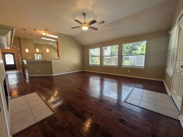 A fantastic angle highlighting the bank of five large windows that flood the space with natural light. This view also shows the living room's open connection to the kitchen and breakfast bar.