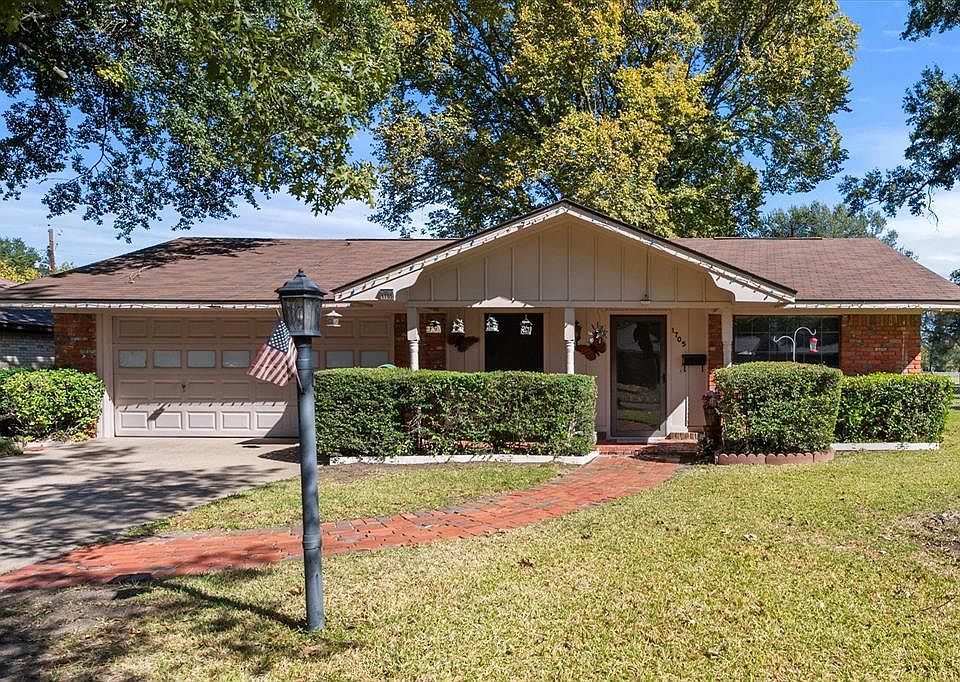Ranch-style home with a front lawn, concrete driveway, a shingled roof, an attached garage, and brick siding