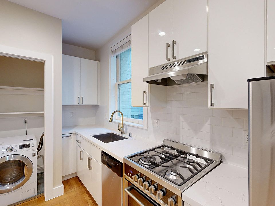 Kitchen with cabinets, refrigerator, stove, range hood, sink, and washer