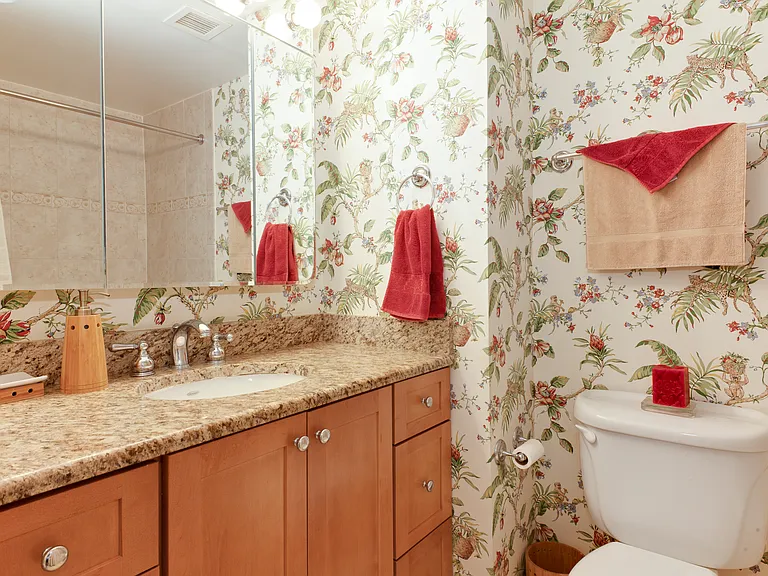 Bathroom granite vanity with large mirror and plenty of storage space.