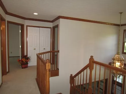 Upstairs hallway with a view of the brass chandelier. Oak staircase is carpeted. Linen closet at end of hallway. White Duck painted walls; Aged Silk off-white carpet; oak trim. Spot lights over hall. Doorways go to front, rear bedrooms and hall bath. - 892 Hunter Ridge Cir