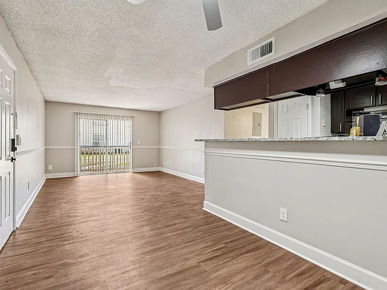 Bright and open living space with wood-style flooring and convenient kitchen pass-through bar.