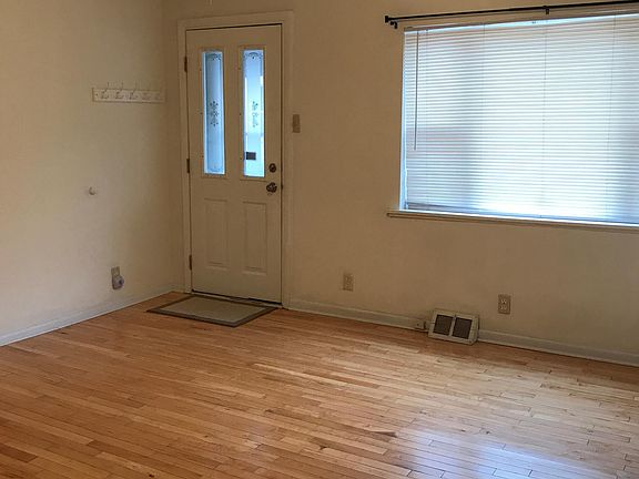 Living room has maple hardwood, ceiling fan and large window for natural light.