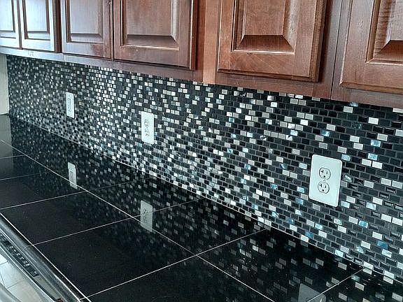 Black granite countertops will handle hot pots and pans. LED lighting installed Above This countertop under the cupboards turn on automatically at night and act as an elegant night light. High-end designer modern tile backsplash features black granite, stainless steel, glass, and iridescent pieces. Match with the countertops and possible stainless steel appliances