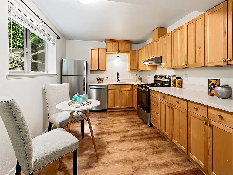 The big, gorgeous kitchen features new stainless steel appliances and a hood fan, a quartz countertop with an under-mount sink, ample maple hardwood cabinets, and eating space.