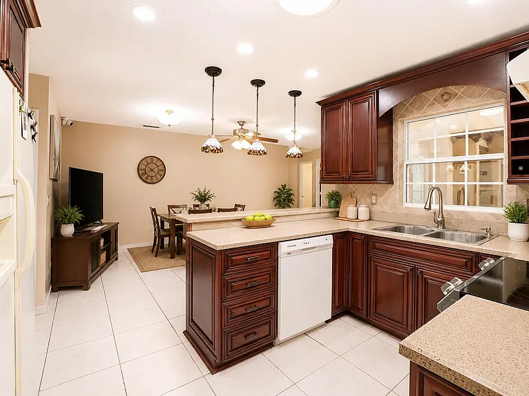 Kitchen with generous counter space, abundant cabinetry, double sink, and a breakfast bar that opens to the dining area.