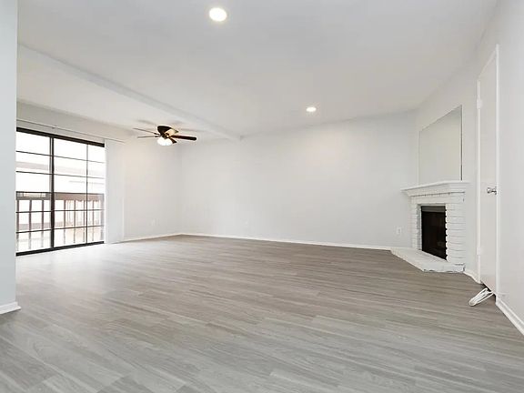 downstairs view of living area, dining area, decorative fireplace and balcony. units vary