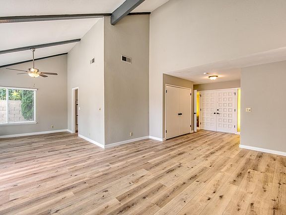 Living room and adjacent dining area, both enhanced by vaulted beam ceiling.