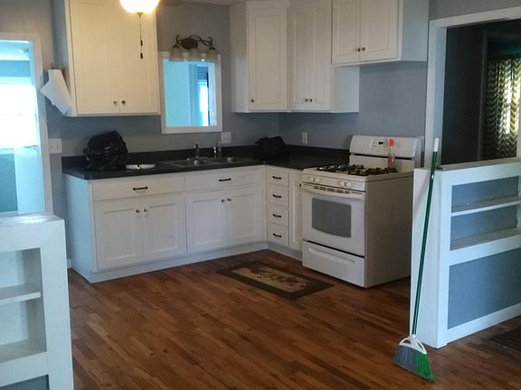 Kitchen with cabinets from Custom Wood Products, gas stove, and large refrigerator.