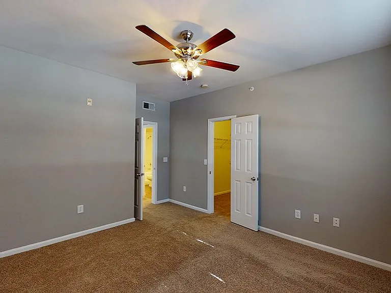 Spacious apartment bedroom with large closet and plush carpet flooring.