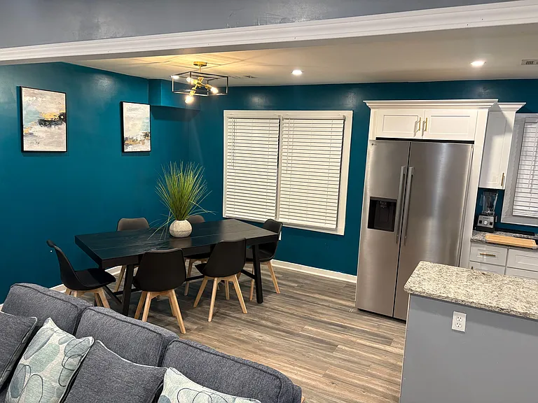 Open dining area beside the kitchen with a full table seating, large windows with blinds, and easy flow to common spaces.