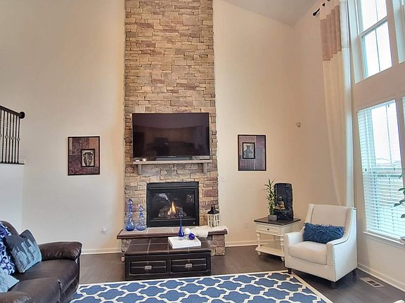 2-story great room with a fireplace and a stone wall.