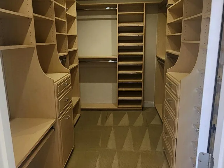 Large walk with custom built in cabinet and sky light in primary bedroom.