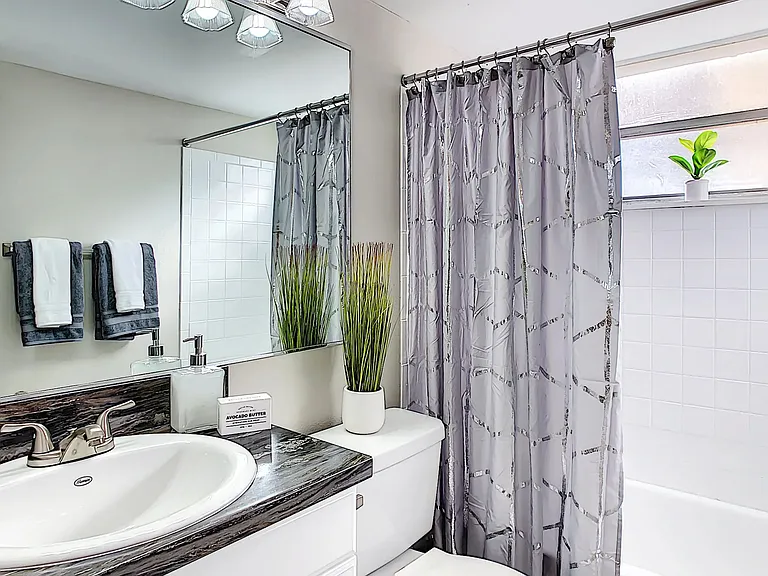 Step into newly renovated bathrooms featuring bold black counters, wood-style flooring, and oversized mirrors for your stylish start.