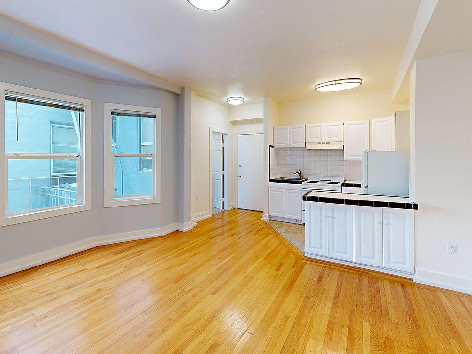 Living room with a window, wood-like flooring, and a view of the kitchen