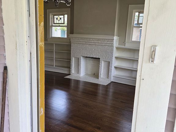 From front porch into Living Room. Bookshelves either side of fireplace, plumbed for gas logs.