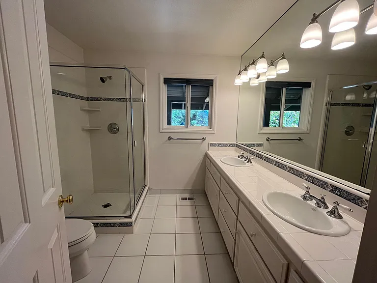 The hallway bathroom is well-appointed with dual sinks and a glass shower enclosure.